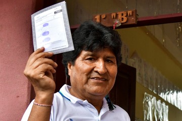 Evo Morales tenant un document devant une maison